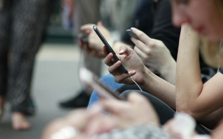 Personas utilizando teléfonos móviles en un contexto de regulación de redes sociales