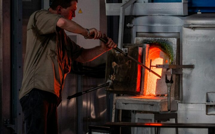 Vidriero trabajando frente a un horno industrial